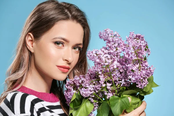 Beautiful young woman with bouquet of lilac flowers on color background — Stock Photo, Image