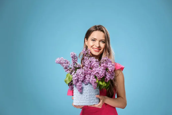 Beautiful young woman with bouquet of lilac flowers on color background — Stock Photo, Image