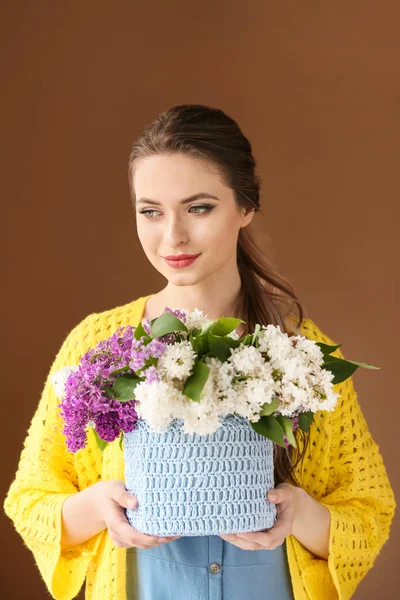 Vacker ung kvinna med bukett av lila blommor på färg bakgrund — Stockfoto
