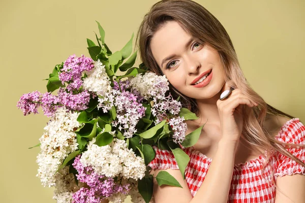 Hermosa mujer joven con ramo de flores lila sobre fondo de color — Foto de Stock