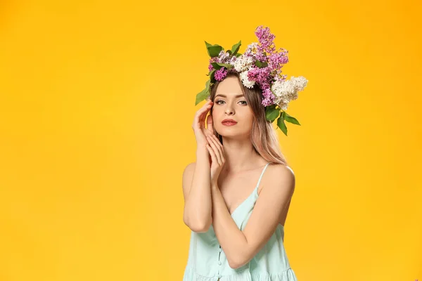 Hermosa mujer joven con flores lila en la cabeza contra el fondo de color —  Fotos de Stock