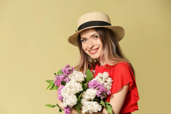 Beautiful young woman with bouquet of lilac flowers on color background — Stock Photo, Image