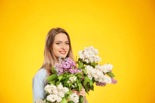 Vacker ung kvinna med bukett av lila blommor på färg bakgrund — Stockfoto