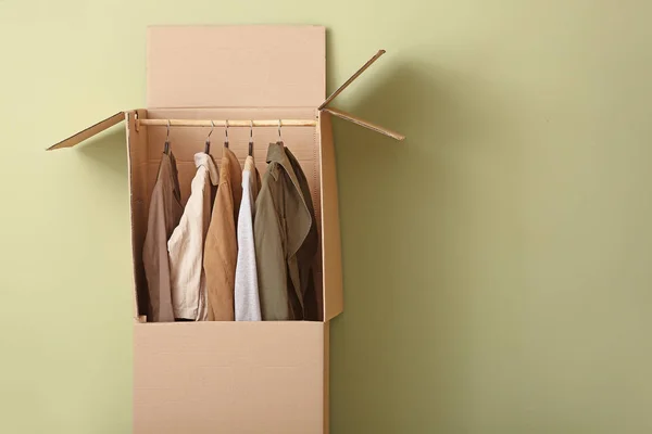 Wardrobe box with clothes on color background — Stock Photo, Image