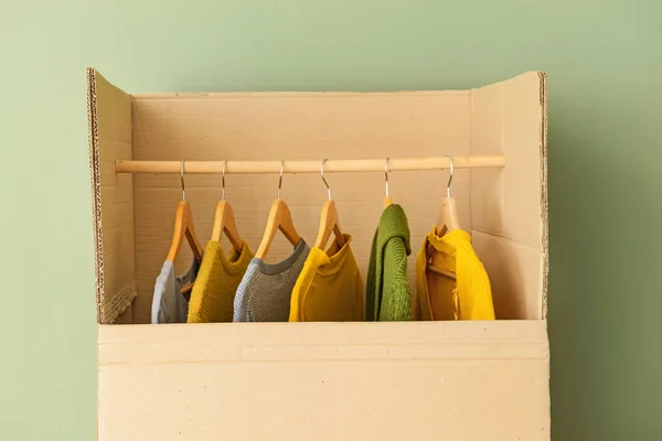 Wardrobe box with clothes near color wall