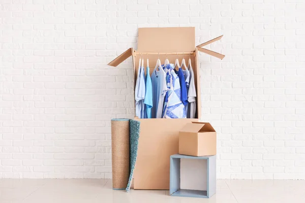 Wardrobe boxes with clothes and rolled carpet near white wall — Stock Photo, Image