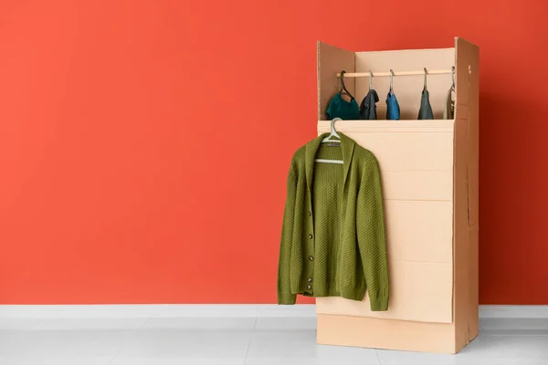 Wardrobe box with clothes near color wall