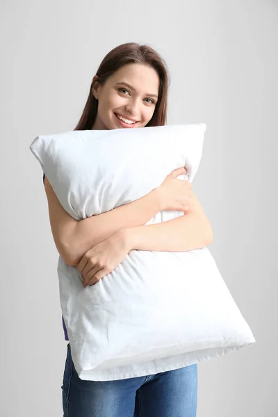 Young woman with pillow on light background — Stock Photo, Image