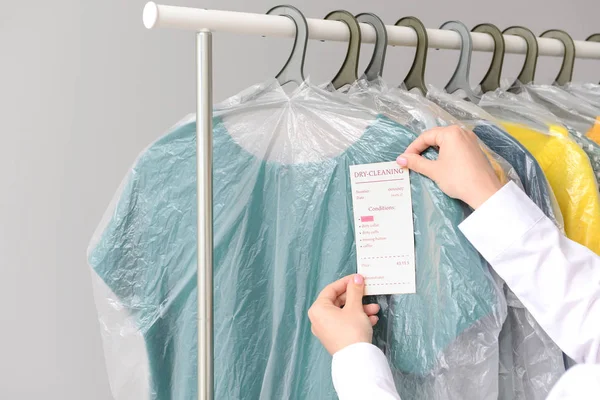 Pekerja dry-cleaner yang menerapkan tag pada pakaian — Stok Foto