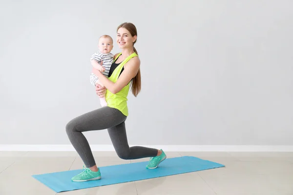 Madre entrenamiento con lindo bebé en el interior —  Fotos de Stock