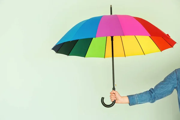 Female hand with stylish rainbow umbrella on color background — Stock Photo, Image