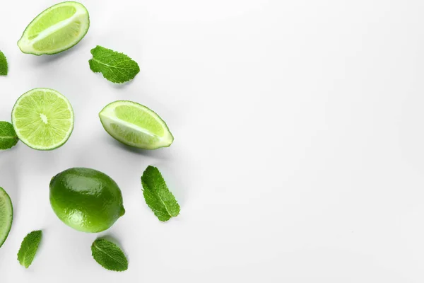 Limas frescas y hojas de menta sobre fondo blanco — Foto de Stock