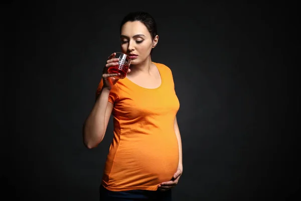 暗い背景にアルコールのガラスを持つ妊娠中の女性 — ストック写真