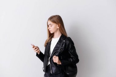 Hafif arka planda cep telefonu ile şık genç kız