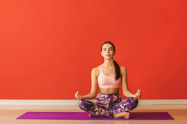 Sporty woman practicing yoga near color wall — Stock Photo, Image