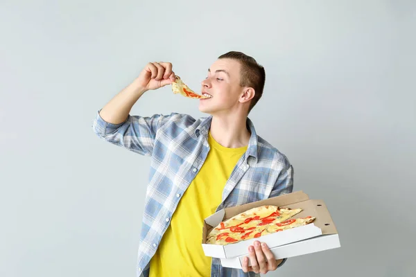 Красивый человек ест вкусную пиццу на светлом фоне — стоковое фото