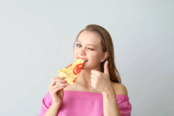 Piękna kobieta jedząca smaczną pizzę na jasnym tle — Zdjęcie stockowe