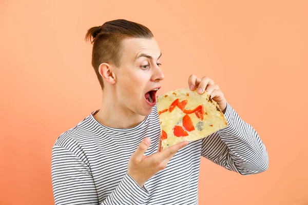 Schöner Mann, der leckere Pizza auf farbigem Hintergrund isst — Stockfoto