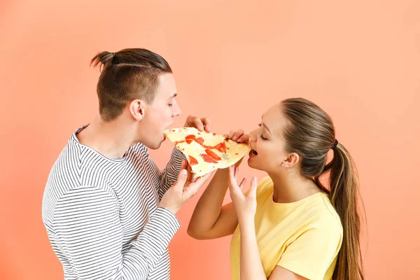 Young couple eating tasty pizza on color background — Stock Photo, Image