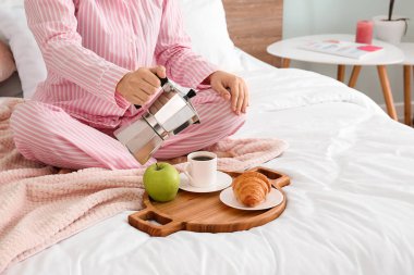 Kadın yatakta lezzetli bir kahvaltı yapıyor.