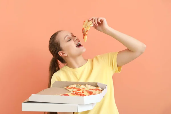 Beautiful woman eating tasty pizza on color background — Stock Photo, Image