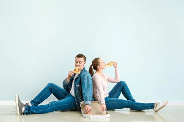 Young couple eating tasty pizza near light wall — Stock Photo, Image