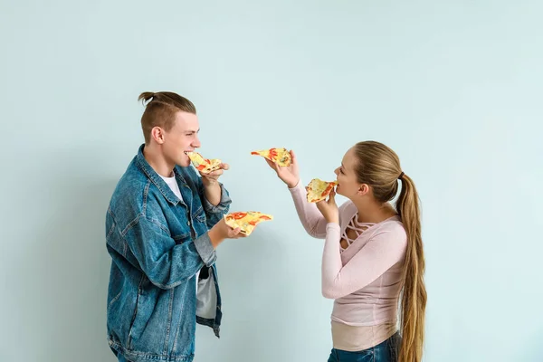 Young couple eating tasty pizza on light background — Stock Photo, Image