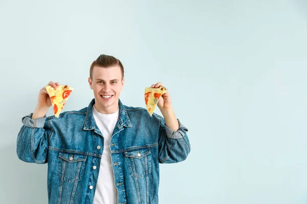 Pohledný muž s chutnou pizzou na světlého pozadí — Stock fotografie