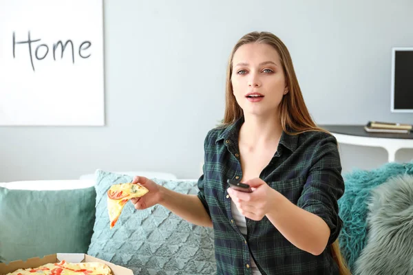 Hermosa mujer comiendo sabrosa pizza y viendo la televisión en casa — Foto de Stock