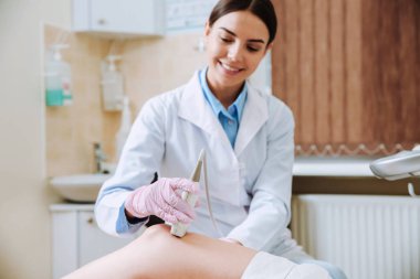 Kadın doktor klinikte kadının ultrason muayenesi yapıyor