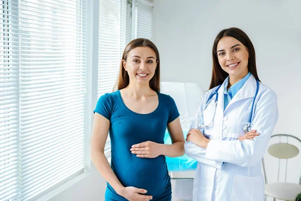 Ginecologista feminina que trabalha com mulher grávida na clínica — Fotografia de Stock