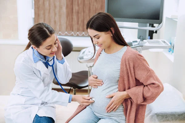 Vrouwelijke gynaecoloog werken met zwangere vrouw in kliniek — Stockfoto