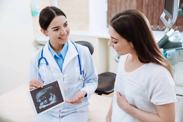 Vrouwelijke ultrasonographer werken met zwangere vrouw in moderne kliniek — Stockfoto