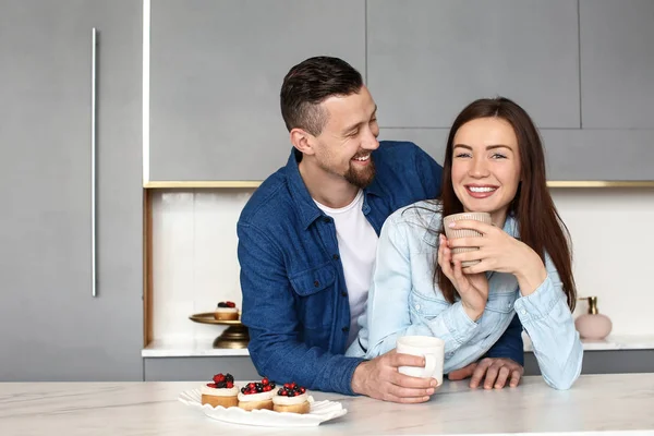 Feliz joven pareja bebiendo té con dulces en casa —  Fotos de Stock