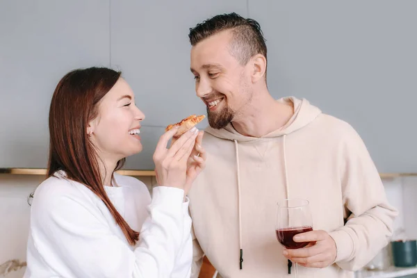Casal feliz beber vinho e comer pizza saborosa em casa — Fotografia de Stock