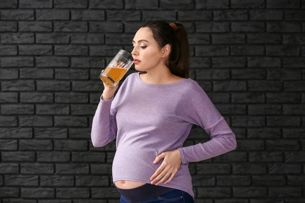 Zwangere vrouw met bier op donkere achtergrond — Stockfoto