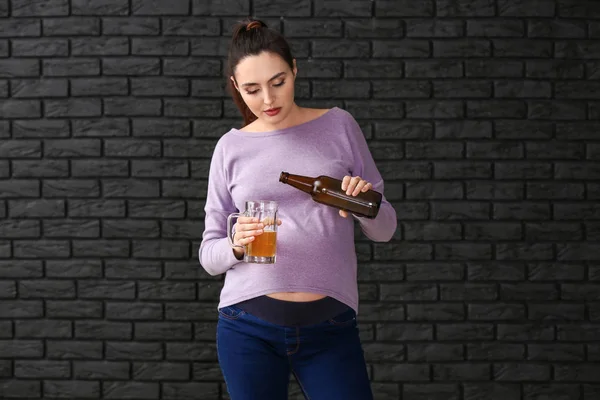 Mulher grávida com cerveja no fundo escuro — Fotografia de Stock