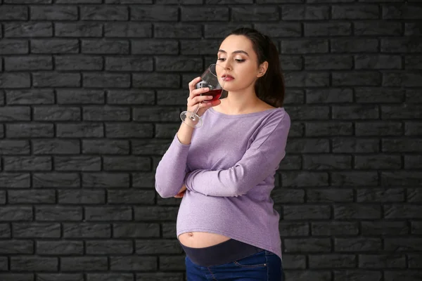 Femme enceinte avec un verre de vin sur fond sombre — Photo