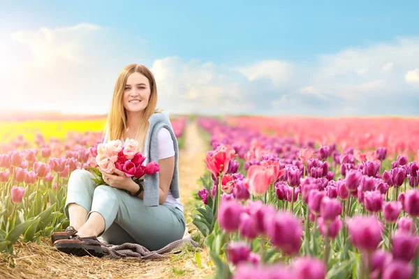 Beautiful young woman in tulip field on spring day — Stock Photo, Image