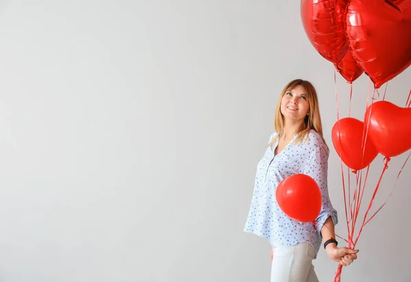 Gri arka planda kalp şeklinde hava balonları olan güzel genç bir kadın. — Stok fotoğraf