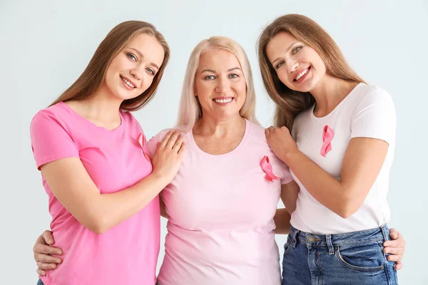 Hermosas mujeres de diferentes edades con cintas de color rosa sobre fondo claro. Concepto de cáncer de mama — Foto de Stock