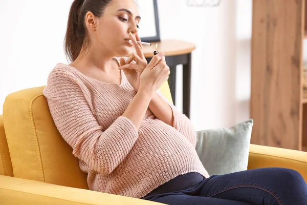 Беременная женщина курит дома — стоковое фото