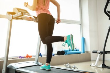 Spor salonundaki koşu bandında antrenman yapan genç bir kadın.