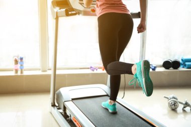 Spor salonundaki koşu bandında antrenman yapan genç bir kadın.