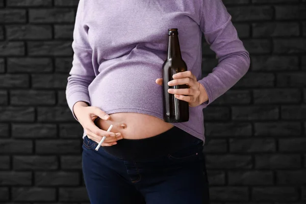 Mulher grávida com cerveja e cigarro no fundo escuro — Fotografia de Stock