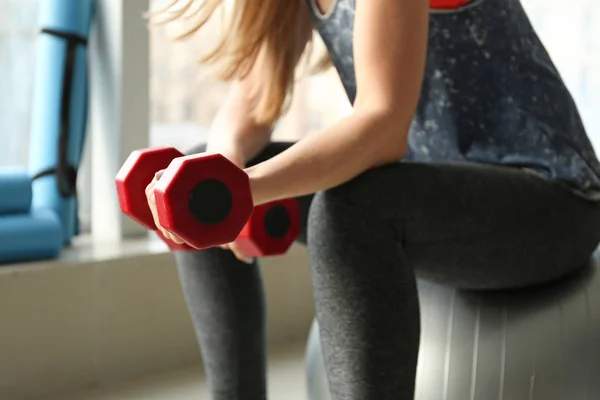 Спортивна молода жінка тренується з гантелями в спортзалі — стокове фото