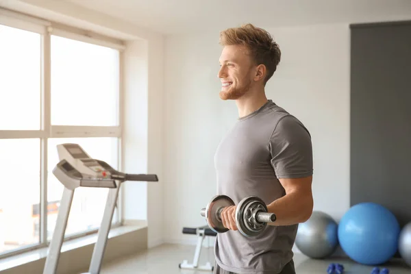 Sporty young man training with dumbbells in gym — Stock Photo, Image