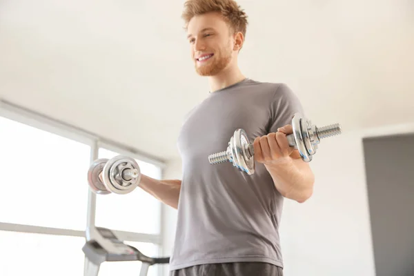 Sporty young man training with dumbbells in gym — Stock Photo, Image