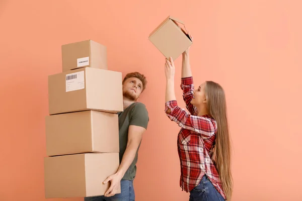 Young couple with many cardboard boxes on color background — Stock Photo, Image