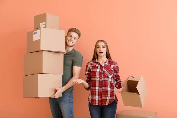 Jong koppel met veel kartonnen dozen op kleur achtergrond — Stockfoto